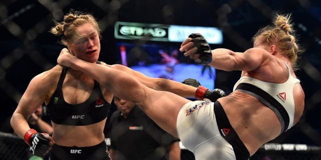 Holly Holm of the US (R) lands a kick to the neck to knock out compatriot Ronda Rousey and win the UFC title fight in Melbourne on November 15, 2015. RESTRICTED TO EDITORIAL USE NO ADVERTISING USE NO PROMOTIONAL USE NO MERCHANDISING USE. AFP PHOTO/Paul CROCK (Photo credit should read PAUL CROCK/AFP/Getty Images)