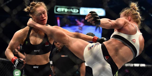 Holly Holm of the US (R) lands a kick to the neck to knock out compatriot Ronda Rousey and win the UFC title fight in Melbourne on November 15, 2015. RESTRICTED TO EDITORIAL USE NO ADVERTISING USE NO PROMOTIONAL USE NO MERCHANDISING USE. AFP PHOTO/Paul CROCK (Photo credit should read PAUL CROCK/AFP/Getty Images)