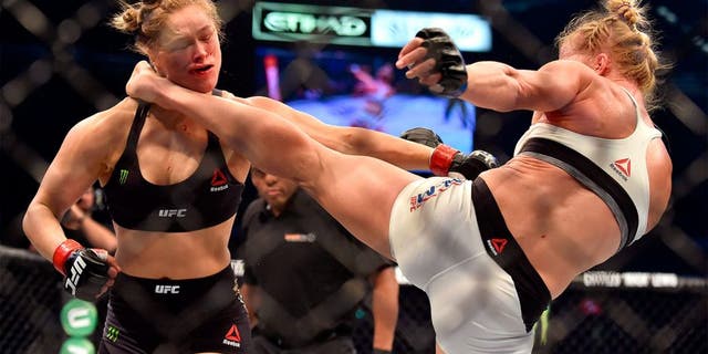 Holly Holm of the US (R) lands a kick to the neck to knock out compatriot Ronda Rousey and win the UFC title fight in Melbourne on November 15, 2015. RESTRICTED TO EDITORIAL USE NO ADVERTISING USE NO PROMOTIONAL USE NO MERCHANDISING USE. AFP PHOTO/Paul CROCK (Photo credit should read PAUL CROCK/AFP/Getty Images)