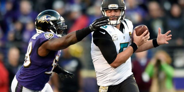 Baltimore Ravens outside linebacker Elvis Dumervil, left, grabs Jacksonville Jaguars quarterback Blake Bortles' face mask in the second half an NFL football game, Sunday, Nov. 15, 2015, in Baltimore. Jacksonville kicked the winning field goal after Baltimore received a face mask penalty on the play. Jacksonville won 22-20. (AP Photo/Gail Burton)