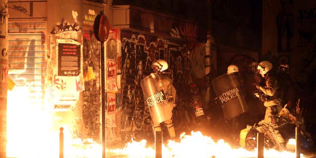 Nov. 15, 2016: Police officers walk past flames from a fire bomb thrown by demonstrators during a protest against the visit of US President Barack Obama in Athens.