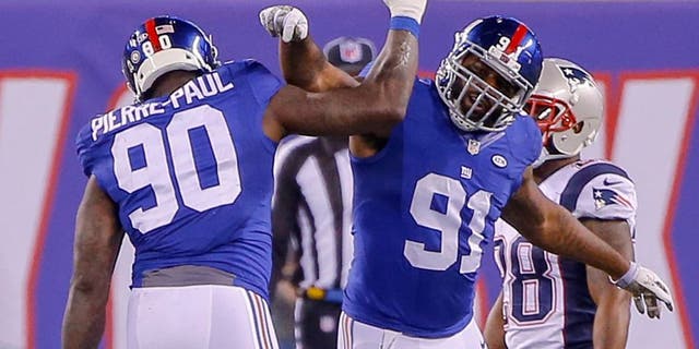 Nov 15, 2015; East Rutherford, NJ, USA; New York Giants defensive end Jason Pierre-Paul (90) celebrates with defensive end Robert Ayers (91) during the fourth quarter against the New England Patriots at MetLife Stadium. Jason Pierre-Paul had to put protection on after hurting his hand by deflecting a pass during the first half. New England Patriots defeat the New York Giants 27-26. Mandatory Credit: Jim O'Connor-USA TODAY Sports