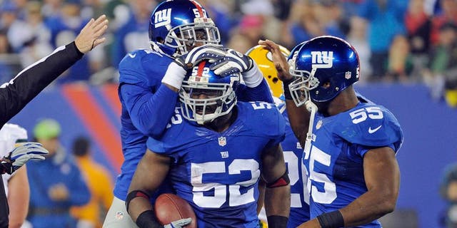 New York Giants' Jon Beason (52) celebrates with teammates Jacquian Williams, left, and Keith Rivers (55) after Beason got an interception during the second half of an NFL football game against the Green Bay Packers, Sunday, Nov. 17, 2013, in East Rutherford, N.J. (AP Photo/Bill Kostroun)