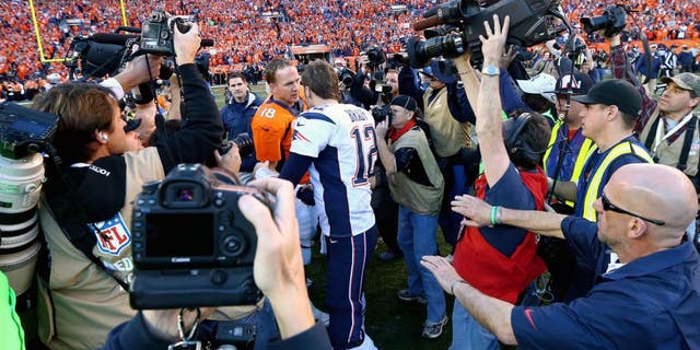 Jan 19, 2014; Denver, CO, USA; Members of the media fight for position to photograph Denver Broncos quarterback Peyton Manning shaking hands with New England Patriots quarterback Tom Brady following the 2013 AFC Championship football game at Sports Authority Field at Mile High. Mandatory Credit: Mark J. Rebilas-USA TODAY Sports
