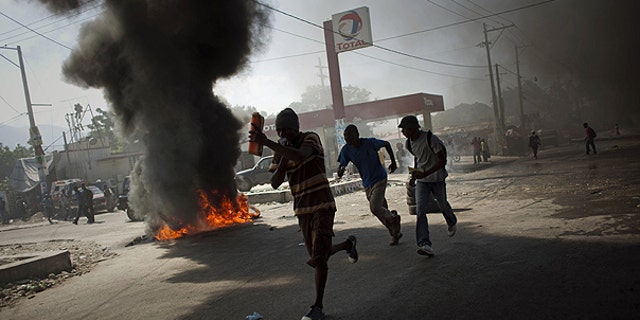 Nov. 18: Demonstrators run past burning tires during a protest in Port-au-Prince, Haiti. Protesters in Haiti's capital clashed with police following days of rioting in northern Haiti over suspicions that U.N. soldiers introduced a cholera epidemic that has killed more than 1,000 people.