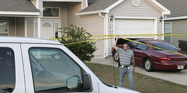 Nov. 20: An investigator lifts police tape to pass under at a home where a woman and three children were slain in Tallahassee, Fla.
