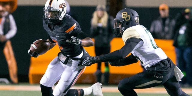 Nov 23, 2013; Stillwater, OK, USA; Oklahoma State Cowboys wide receiver Josh Stewart (5) runs the ball during the first quarter against Baylor Bears safety Terrell Burt (13) at Boone Pickens Stadium. Mandatory Credit: Richard Rowe-USA TODAY Sports