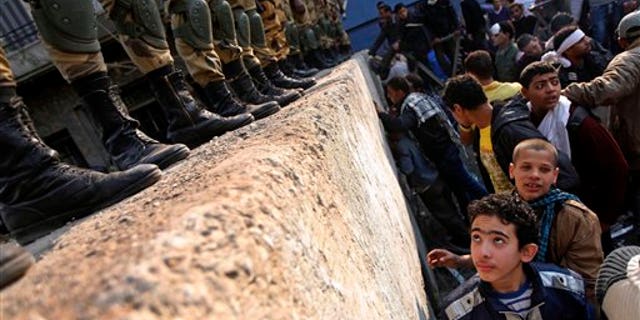 November 24, 2011: A boy looks at Egyptian Army soldiers standing guard atop a concrete block barricade on the street between Tahrir Square and the interior ministry in Cairo, Egypt.