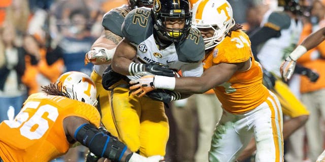 Nov 22, 2014; Knoxville, TN, USA; Missouri Tigers running back Russell Hansbrough (32) rushes against Tennessee Volunteers defensive lineman Curt Maggitt (56) and linebacker Jalen Reeves-Maybin (34) during the first half at Neyland Stadium. Mandatory Credit: Jim Brown-USA TODAY Sports