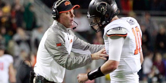 Nov 22, 2014; Waco, TX, USA; Oklahoma State Cowboys head coach Mike Gundy talks with quarterback Mason Rudolph (10) during a time out in the second quarter against the Baylor Bears at McLane Stadium. Mandatory Credit: Tim Heitman-USA TODAY Sports
