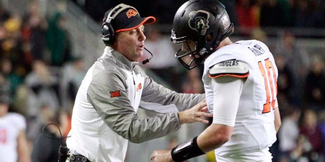 Nov 22, 2014; Waco, TX, USA; Oklahoma State Cowboys head coach Mike Gundy talks with quarterback Mason Rudolph (10) during a time out in the second quarter against the Baylor Bears at McLane Stadium. Mandatory Credit: Tim Heitman-USA TODAY Sports