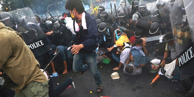 Nov. 24, 2012: Anti-government protesters try to flee from tear gas fired by police in Bangkok.