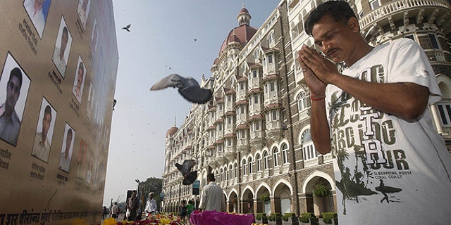 Nov. 26: A man pays homage in front of portraits of police officers killed in the Mumbai terror attack outside the Taj Mahal Palace hotel, one of the sites of the attack, on the second anniversary of the attack in Mumbai, India.