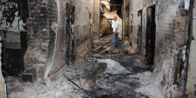 FILE - In this Oct. 16, 2015, file photo, an employee of Doctors Without Borders stands inside the charred remains of their hospital after it was hit by a U.S. airstrike in Kunduz, Afghanistan.