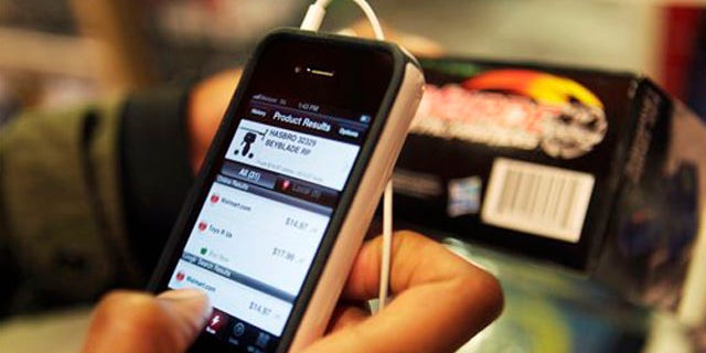 November 28, 2011: Robert Drayton uses his smartphone to help him find the right gifts and compare prices at Toys R Us in New York.