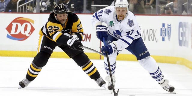 Nov 26, 2014; Pittsburgh, PA, USA; Pittsburgh Penguins right wing Craig Adams (27) and Toronto Maple Leafs center Leo Komarov (47) chase the puck during the third period at the CONSOL Energy Center. The Penguins won 4-3 in overtime. Mandatory Credit: Charles LeClaire-USA TODAY Sports