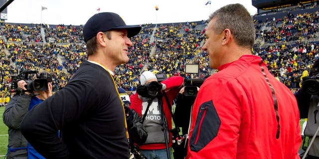 Michigan head coach Jim Harbaugh, left, talks with Ohio State head coach Urban Meyer, right, on the Michigan Stadium field before an NCAA college football game in Ann Arbor, Mich., Saturday, Nov. 28, 2015. (AP Photo/Tony Ding)