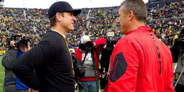 Michigan head coach Jim Harbaugh, left, talks with Ohio State head coach Urban Meyer, right, on the Michigan Stadium field before an NCAA college football game in Ann Arbor, Mich., Saturday, Nov. 28, 2015. (AP Photo/Tony Ding)