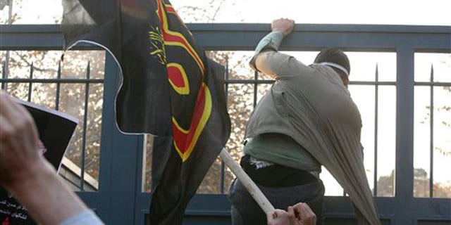 November 29, 2011: An Iranian protester tries to enter the British Embassy, as he is prevented by police.