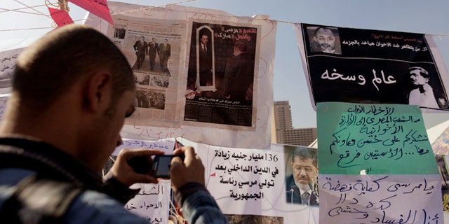 Nov. 29, 2012: An Egyptian protester photographs newspapers and placards on display in a makeshift museum in Tahrir Square in Cairo, Egypt.