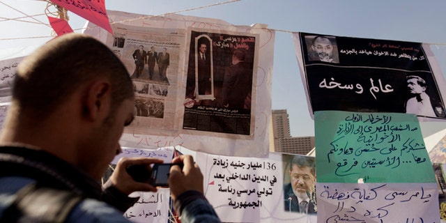 Nov. 29, 2012: An Egyptian protester photographs newspapers and placards on display in a makeshift museum in Tahrir Square in Cairo, Egypt.