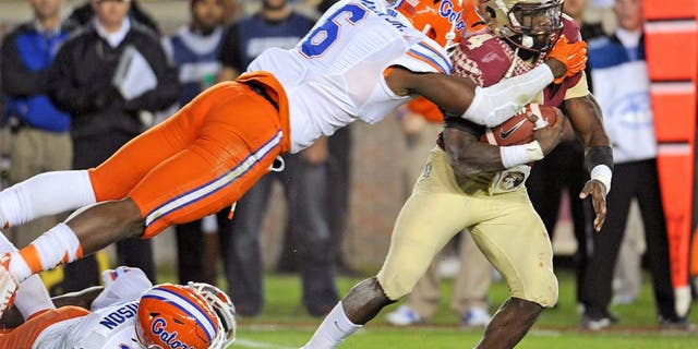 Nov 29, 2014; Tallahassee, FL, USA; Florida State Seminoles running back Dalvin Cook (4) runs the ball past Florida Gators defensive lineman Dante Fowler Jr. (6) and linebacker Antonio Morrison (3) during the game at Doak Campbell Stadium. Mandatory Credit: Melina Vastola-USA TODAY Sports