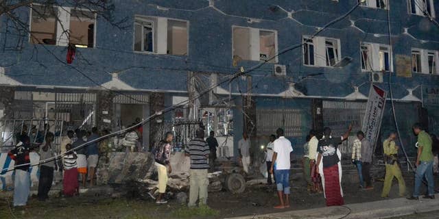Somali security forces and civilians gather outside the Weheliye hotel after it was stormed by militants in Mogadishu, Somalia, Friday, July 10, 2015. Suspected Islamic militant gunmen stormed two hotels in Mogadishu, a Somali police official said Friday. (AP Photo)
