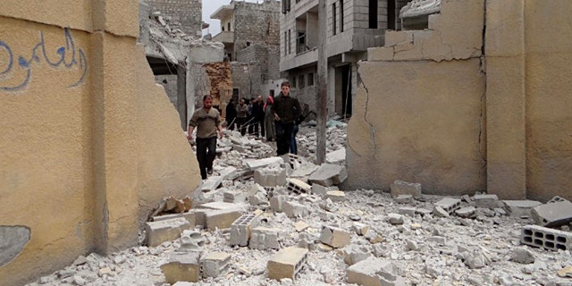 April 12, 2015: This photo posted by the anti-government activist website of the Syrian Observatory for Human Rights, which has been verified and is consistent with other AP reporting, shows Syrians walking at the damaged backyard of a school after an airstrike, in Ansari neighborhood in Aleppo. (Website of the Syrian Observatory for Human Rights via AP)