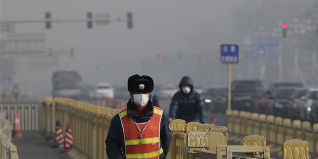 A traffic warden wearing a protection mask walks on a street near Tiananmen Square in Beijing as the capital of China is blanketed by heavy smog in this file photo.