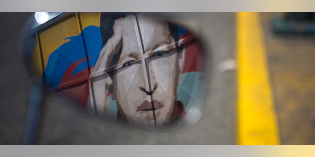June 29: A motorcycle mirror reflects a painting depicting Venezuela's President Hugo Chavez in Caracas, Venezuela.AP Photo/Ariana Cubillos)