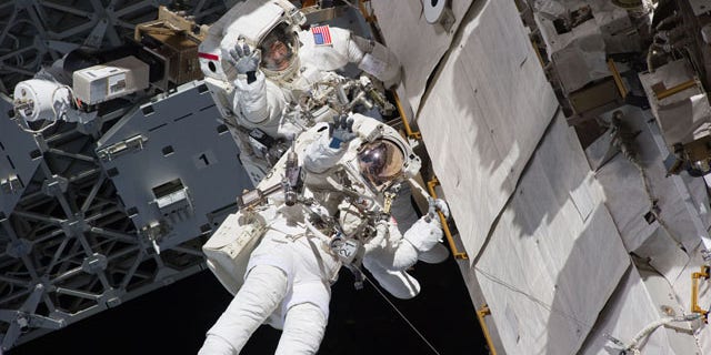 Astronauts Steve Bowen and Alvin Drew wave during the first spacewalk of their STS-133 mission on Feb. 28, 2011 while working outside the International Space Station during the final flight of space shuttle Discovery.