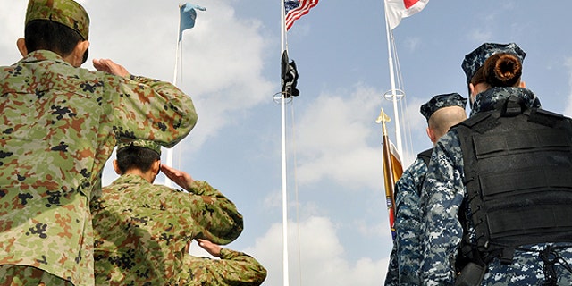 Dec. 3: Japanese Self-Defense Forces, left, and U.S. military personnel salute at the launching ceremony of a base defense exercise at the start of the annual joint military drills 'Keen Sword' in Sasebo, southern Japan.