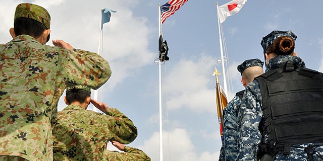 Dec. 3: Japanese Self-Defense Forces, left, and U.S. military personnel salute at the launching ceremony of a base defense exercise at the start of the annual joint military drills 'Keen Sword' in Sasebo, southern Japan.