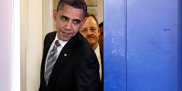 Dec. 7: President Obama, followed by White House Press Secretary Robert Gibbs, slides past the pocket door to the briefing room as he walks out to begin his news conference at the White House in Washington.