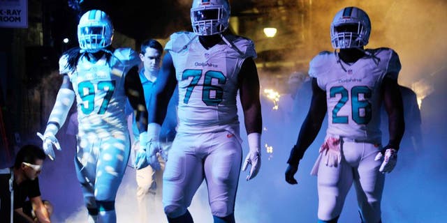 Dec 7, 2014; Miami Gardens, FL, USA; Miami Dolphins linebacker Kelvin Sheppard (left), defensive end Terrence Fede (center) and running back Knowshon Moreno (right) prepare to take the field before a game against the Baltimore Ravens at Sun Life Stadium. Mandatory Credit: Steve Mitchell-USA TODAY Sports