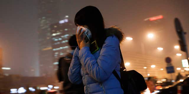 Dec. 9, 2015: A woman covers her face with a mask as she rushes to a subway station on a heavily polluted day in Beijing.