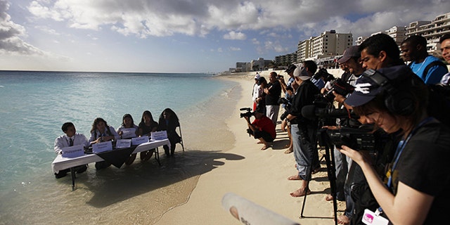 Dec. 9: Environmental activists from 350.org, left, demonstrate before the cameras of journalists during the United Nations Climate Change Conference in Cancun, Mexico.