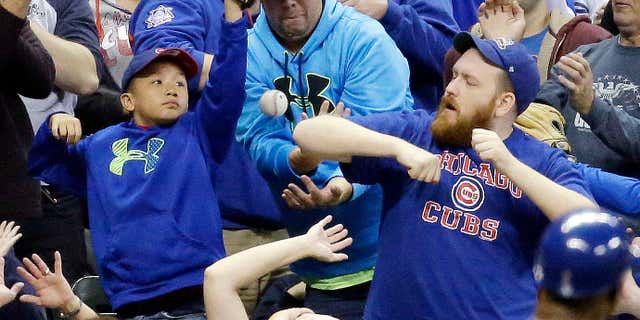 FILE - In this Oct. 2, 2015, file photo, fans go after a foul ball hit by Chicago Cubs' Dexter Fowler during the third inning of a baseball game against the Milwaukee Brewers, in Milwaukee.