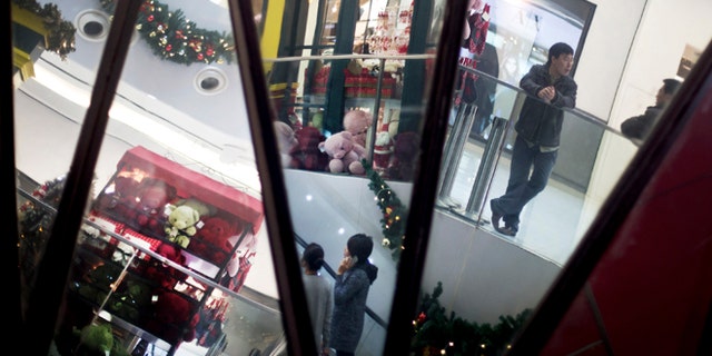 Dec. 10, 2012: Chinese shoppers and Christmas decorations are reflected in mirrors inside a shopping mall in Beijing.