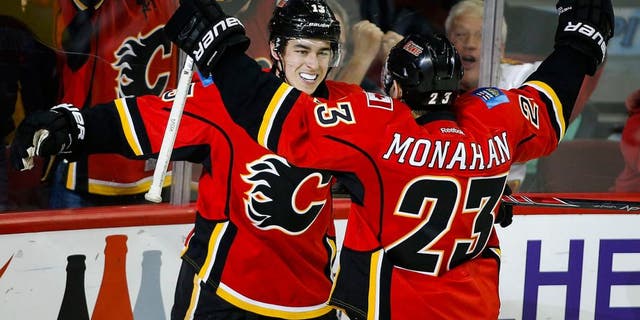 Calgary Flames' Johnny Gaudreau, left, celebrates his game-winning goal with teammate Sean Monahan during third period NHL hockey action against the Buffalo Sabres, in Calgary, on Thursday, Dec. 10, 2015. (Jeff McIntosh/The Canadian Press via AP) MANDATORY CREDIT