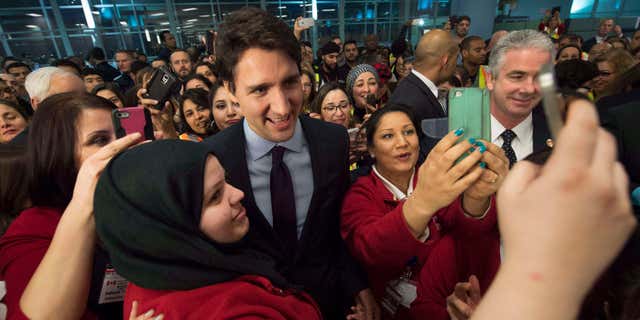 Dec. 10, 2015: Canadian Prime Minister Justin Trudeau, centre, poses for a selfies with workers before he greets refugees from Syria at Pearson International airport, in Toronto.