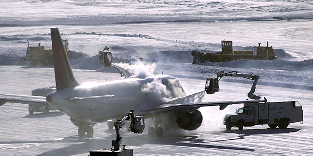 Dec. 12: A plane is de-iced before take-off while snowplows clear the runway at Minneapolis-St. Paul International Airport in Minneapolis.