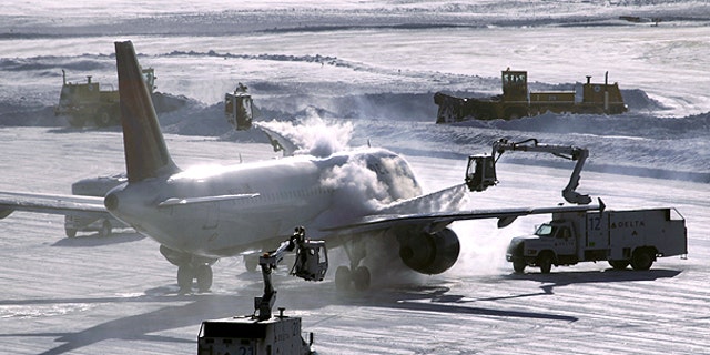 Dec. 12: A plane is de-iced before take-off while snowplows clear the runway at Minneapolis-St. Paul International Airport in Minneapolis.