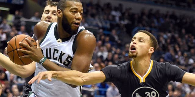 Dec 12, 2015; Milwaukee, WI, USA; Milwaukee Bucks center Greg Monroe (15) grabs a rebound against Golden State Warriors guard Stephen Curry (30) in the second quarter at BMO Harris Bradley Center. Mandatory Credit: Benny Sieu-USA TODAY Sports