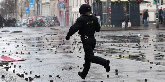 In this Dec. 12, 2015 picture a policeman crosses a street after clashes with left-wing protesters in Leipzig, Germany.