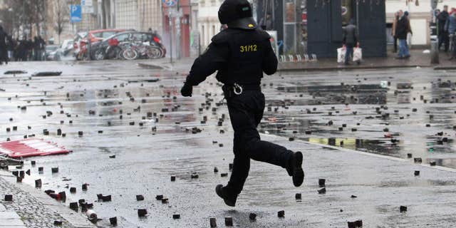 In this Dec. 12, 2015 picture a policeman crosses a street after clashes with left-wing protesters in Leipzig, Germany.