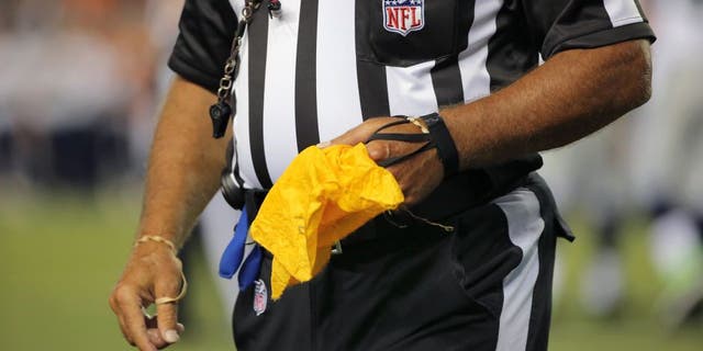 DENVER, CO - AUGUST 07: A referee collects his penalty flag as the Seattle Seahawks face the Denver Broncos during preseason action at Sports Authority Field at Mile High on August 7, 2014 in Denver, Colorado. The Broncos defeated the Seahawks 21-16. (Photo by Doug Pensinger/Getty Images)