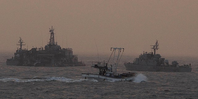 Dec. 19: A South Korean fishing boat sails by a South Korean navy facility and navy ship near Yeonpyeong island, South Korea.