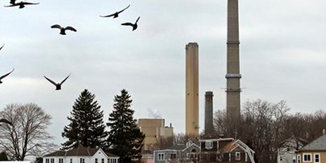 December 14, 2011: Pigeons fly past as the stacks of Dominion's power plant tower over a nearby neighborhood in Salem, Mass.