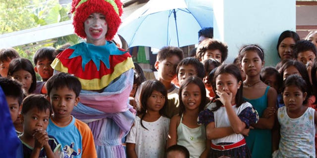 Dec. 25: An entertainer dressed as a clown watches another performance together with Mayon volcano children evacuees during a Christmas celebration at an evacuation center in Legazpi City, Philippines.